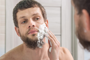 Image showing A man is applying shaving foam to his face preparing to shave