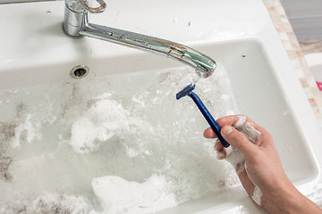 Image showing The man\'s hand washes the shaver under the stream of water