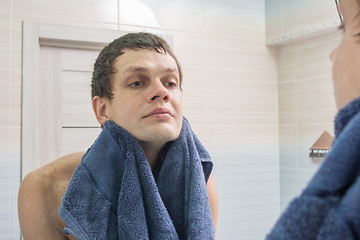 Image showing A young man shaved and washed himself wiping himself dry with a towel