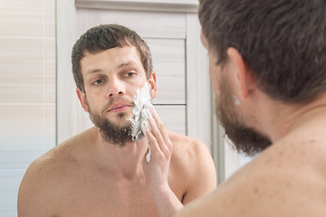 Image showing A man is applying shaving foam to his face preparing to shave