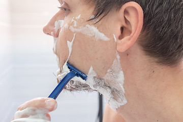 Image showing The guy shaves his left cheek, close-up