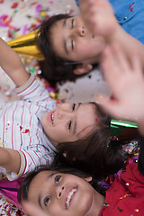 Image showing kids  blowing confetti while lying on the floor