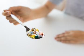 Image showing close up of female hand holding spoon with pills