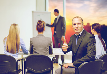 Image showing businessman with team showing thumbs up at office