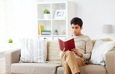 Image showing man sitting on sofa and reading book at home