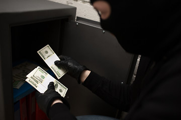 Image showing thief stealing money from safe at crime scene