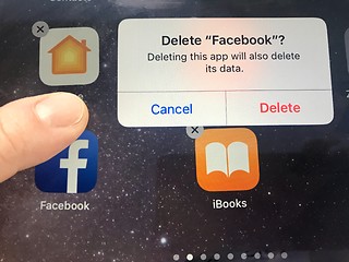 Image showing Macro image of a finger about to delete the Facebook app from an iPad screen - might be due to data privacy issues, Facebook is currently facing
