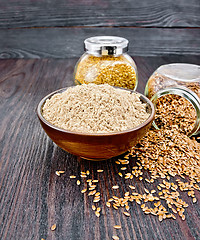 Image showing Flour linen in bowl with seeds in jars on dark board