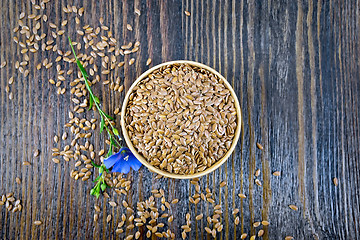 Image showing Flaxen brown seed in bowl with flower on board top