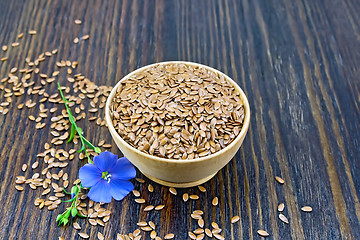 Image showing Flaxen brown seed in bowl with flower on dark board