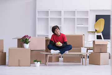 Image showing boy sitting on the table with cardboard boxes around him