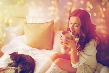 Image showing happy woman with cup of coffee in bed at home