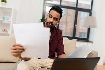 Image showing upset man with laptop and papers at home