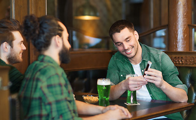 Image showing friends with smartphone drinking green beer at pub