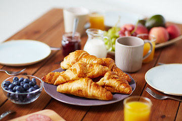 Image showing plate of croissants on wooden table at breakfast