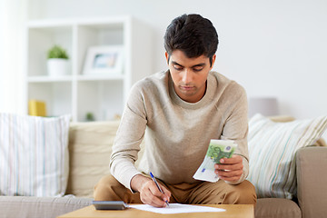 Image showing man with money and calculator filling papers