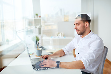 Image showing happy businessman typing on laptop at office