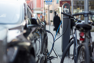 Image showing Charging modern electric car on the street as future of automotive industry.