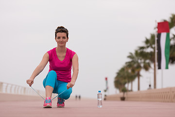 Image showing Young woman tying shoelaces on sneakers