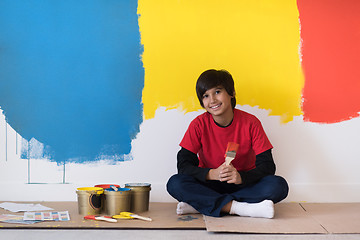 Image showing young boy painter resting after painting the wall