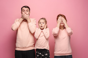 Image showing Surprised young family looking at camera on pink