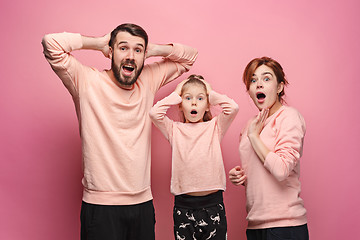 Image showing Surprised young family looking at camera on pink