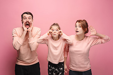 Image showing Surprised young family looking at camera on pink