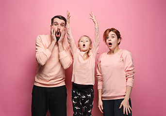 Image showing Surprised young family looking at camera on pink