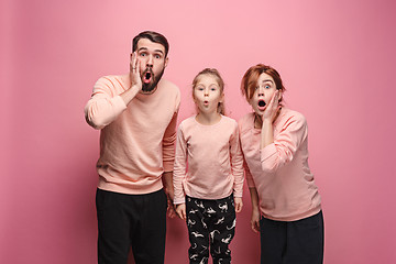 Image showing Surprised young family looking at camera on pink