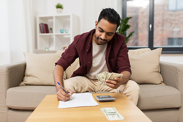 Image showing man with money and calculator filling papers