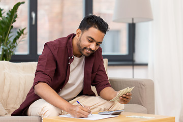 Image showing man with money and calculator filling papers