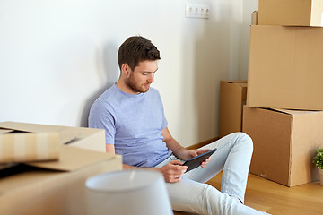 Image showing man with tablet pc and boxes moving to new home