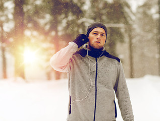 Image showing sports man with earphones in winter forest