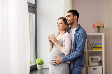 Image showing man hugging pregnant woman at window at home