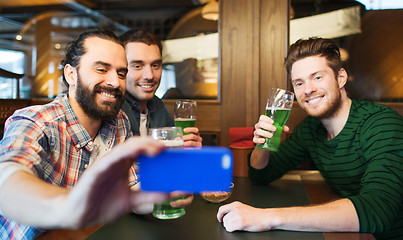 Image showing friends taking selfie with green beer at pub