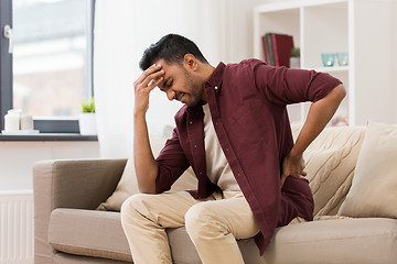 Image showing unhappy man suffering from backache at home