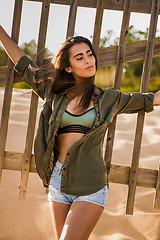 Image showing Beautiful young woman posing near a wood fence