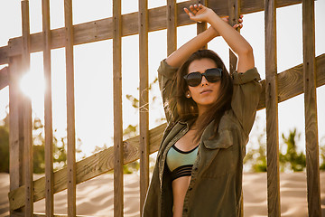 Image showing Beautiful young woman posing near a wood fence