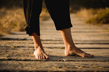 Image showing Female legs on a wood path