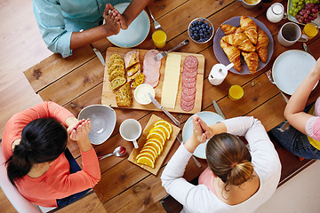 Image showing group of people at table praying before meal