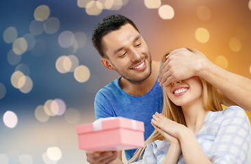 Image showing happy couple with present over lights background