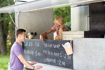 Image showing saleswoman at food truck serving male customer