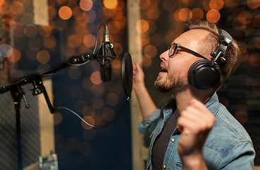 Image showing man with headphones singing at recording studio