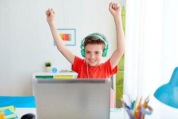 Image showing boy with headphones playing video game on laptop