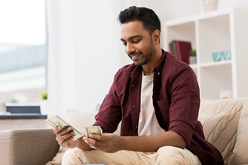 Image showing smiling man counting money at home