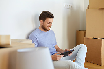 Image showing man with tablet pc and boxes moving to new home