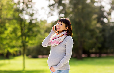 Image showing pregnant asian woman calling on smartphone at park