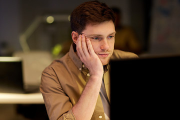 Image showing tired or bored man on table at night office