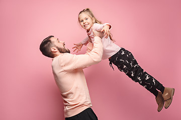 Image showing cheerful father playing with daughter on pink