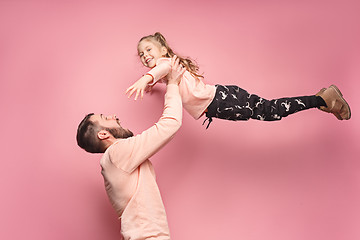 Image showing cheerful father playing with daughter on pink